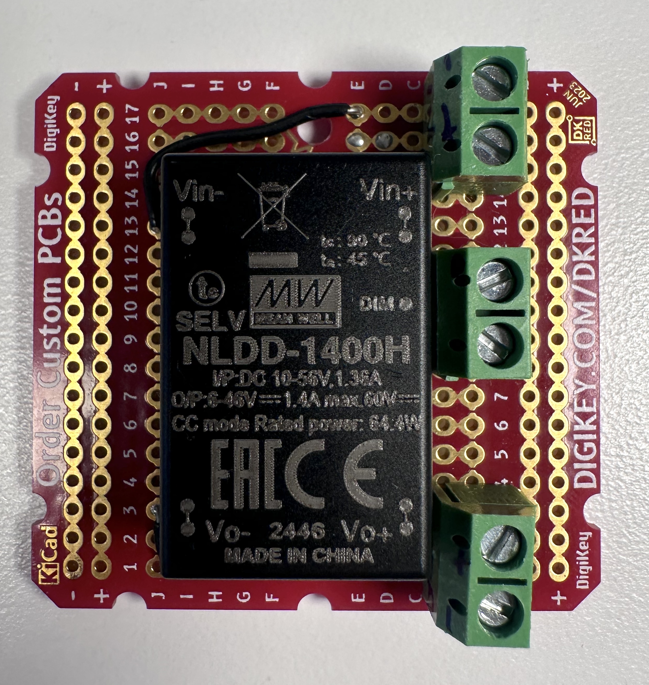 Photo of a  Meanwell NLDD1400H LED driver soldered to a printed circuit board, with screw terminals for connections, front view